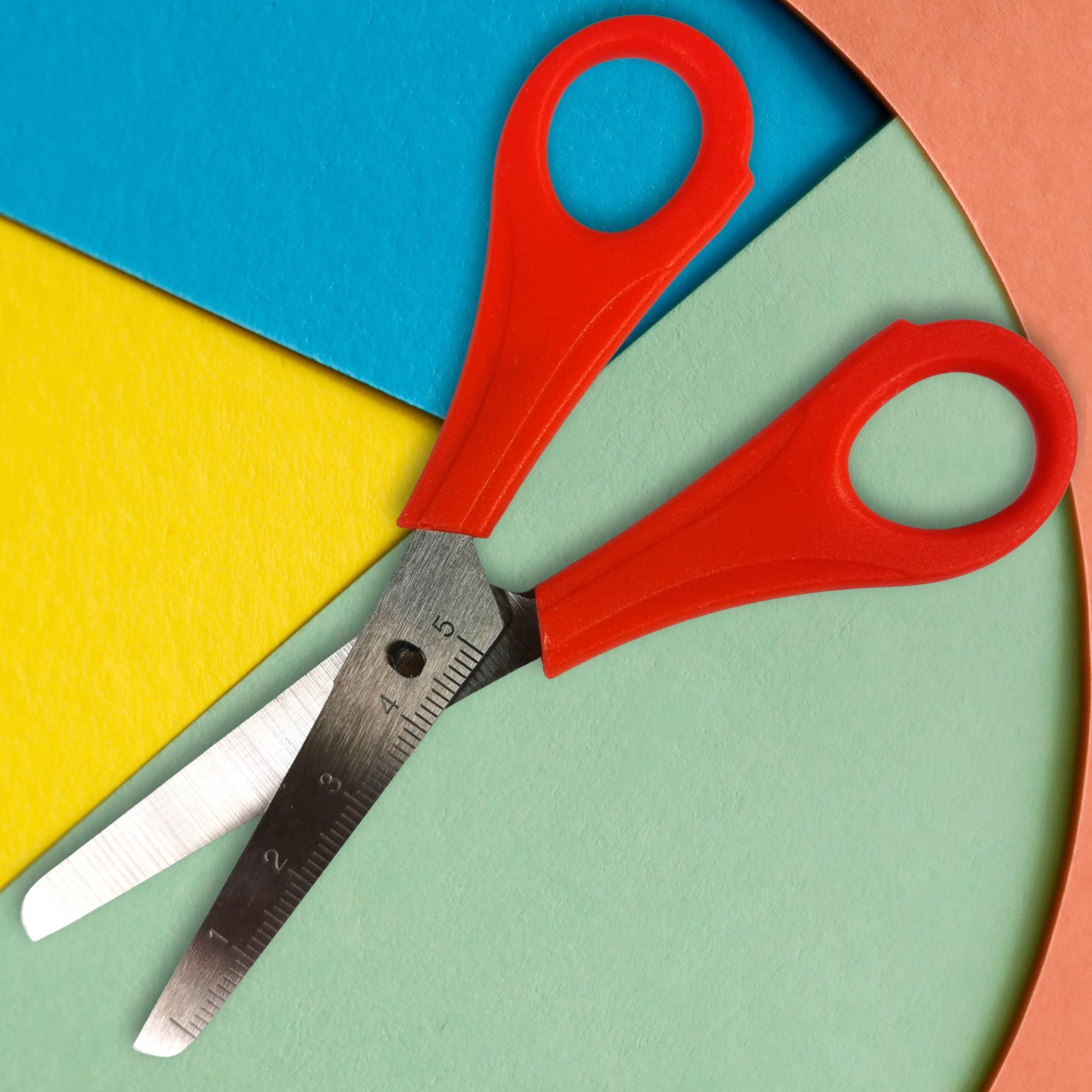 Red scissors on a colorful geometric background