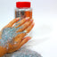 Hand with glittery powder and a jar of glitter on a white background