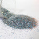 silver Glitter spilling from a clear container on a white surface